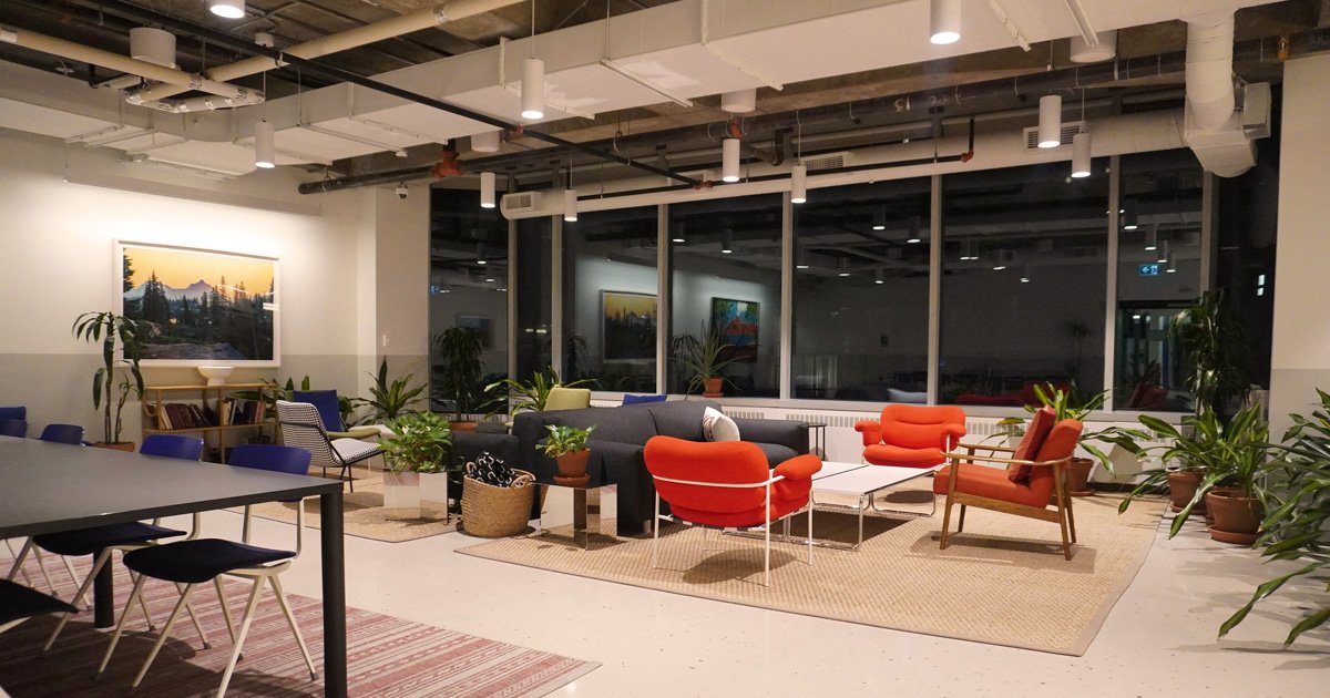 Clean, modern office lounge space with warm lighting and organized seating