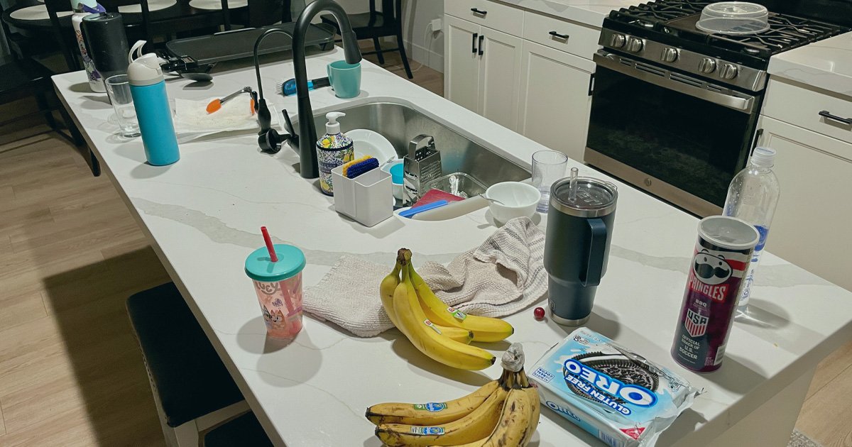 Kitchen island covered with dishes, snacks, cups, and towels after hosting family gatherings during the holidays, symbolizing emotional and physical exhaustion from trying to hold everything together.